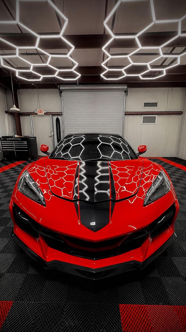 Red Corvette Z06 in the shop under hexagon lighting after paint protection film install
