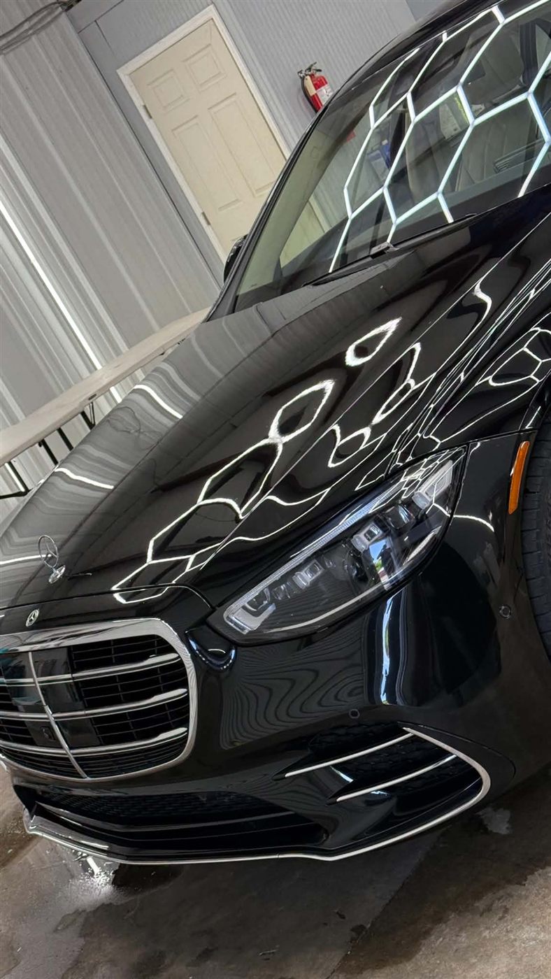 Black Mercedes S-Class under shop lighting with fresh film